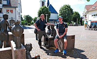 Rast auf dem Holter Kirchplatz: Tyler Larkin und Stefan Boes durchwandern Ostwestfalen-Lippe von Süden nach Norden. Gestern haben sie sich das Quellgebiet der Ems angeschaut und sind durch die Moosheide gewandert. - Gunter Held Rast auf dem Holter Kirchplatz: Tyler Larkin und Stefan Boes durchwandern Ostwestfalen-Lippe von Süden nach Norden. Gestern haben sie sich das Quellgebiet der Ems angeschaut und sind durch die Moosheide gewandert. - Gunter Held