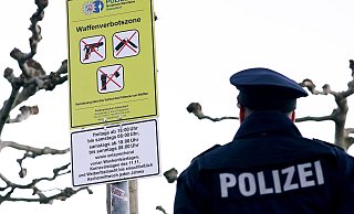 Ein Polizist steht auf der Düsseldorfer Rheinufer-Promenade vor einem Schild zur Waffenverbotszone. - David Young / dpa Ein Polizist steht auf der Düsseldorfer Rheinufer-Promenade vor einem Schild zur Waffenverbotszone. - David Young / dpa