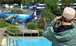 Denis Kelle fotografiert im Freibad Gadderbaum sein eigenes Werk - hinten freut sich Hannelore Pfaff mit ihm. - Kurt Ehmke Denis Kelle fotografiert im Freibad Gadderbaum sein eigenes Werk - hinten freut sich Hannelore Pfaff mit ihm. - Kurt Ehmke