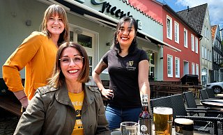 „Wir sind noch da!" Auch Carolin Kramme (von links), Kathrin Dudding und Lan Nguyen dürfen draußen, im Biergarten vor dem Pub „Green’s", ab dem heutigen Donnerstag wieder Gäste bewirten. - Andreas Frücht „Wir sind noch da!" Auch Carolin Kramme (von links), Kathrin Dudding und Lan Nguyen dürfen draußen, im Biergarten vor dem Pub „Green’s", ab dem heutigen Donnerstag wieder Gäste bewirten. - Andreas Frücht