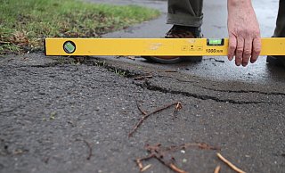 Mit einer Wasserwaage dokumentiert Johannes Lübeck die Unebenheiten des Radwegs an der Wiehenstraße. - Björn Kenter Mit einer Wasserwaage dokumentiert Johannes Lübeck die Unebenheiten des Radwegs an der Wiehenstraße. - Björn Kenter