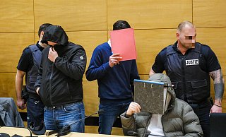 Der Hauptangeklagte passiert hinter einer Aktenmappe versteckt, die beiden Mitangeklagten. - Andreas Zobe Der Hauptangeklagte passiert hinter einer Aktenmappe versteckt, die beiden Mitangeklagten. - Andreas Zobe