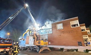 Während ein großer Bagger mit Greifer Teile des verkohlten Daches der Nieheimer Sparkasse herunterholt, wird das Feuer von Drehleitern aus gelöscht. - David Schellenberg Während ein großer Bagger mit Greifer Teile des verkohlten Daches der Nieheimer Sparkasse herunterholt, wird das Feuer von Drehleitern aus gelöscht. - David Schellenberg