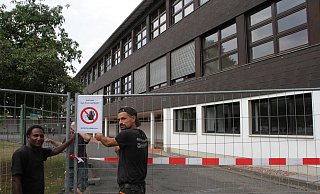 Absperrung: Bauarbeiter bringen ein Schild "Betreten verboten" am Bauzaun an, der rund um den Altbau steht. Das Schulgebäude wird jetzt komplett eingerüstet. - Diete Scholz Absperrung: Bauarbeiter bringen ein Schild "Betreten verboten" am Bauzaun an, der rund um den Altbau steht. Das Schulgebäude wird jetzt komplett eingerüstet. - Diete Scholz
