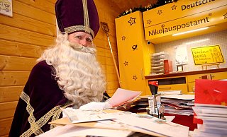 Ein als Nikolaus verkleideter Mann sitzt im Nikolauspostamt in St. Nikolaus vor vielen Briefen. - --/Festausschuss St. Nikolaus/dpa Ein als Nikolaus verkleideter Mann sitzt im Nikolauspostamt in St. Nikolaus vor vielen Briefen. - --/Festausschuss St. Nikolaus/dpa