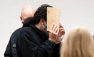 Der Angeklagte (M) hält sich im Saal des Landgerichts eine Aktenmappe vor das Gesicht. - picture alliance/dpa Der Angeklagte (M) hält sich im Saal des Landgerichts eine Aktenmappe vor das Gesicht. - picture alliance/dpa