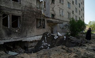 Eine Frau neben dem Krater einer Explosion, die in Lyman eine Wohnung und einen Keller eines Wohnhauses beschädigt hat. - Foto: Leo Correa/AP/dpa Eine Frau neben dem Krater einer Explosion, die in Lyman eine Wohnung und einen Keller eines Wohnhauses beschädigt hat. - Foto: Leo Correa/AP/dpa