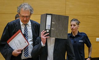 Der 21-jährige Mörder hält einen Aktenordner vor sein Gesicht. Sein Verteidiger, Georg Schulze, begleitet ihn am Bielefelder Landgericht. - Andreas Zobe Der 21-jährige Mörder hält einen Aktenordner vor sein Gesicht. Sein Verteidiger, Georg Schulze, begleitet ihn am Bielefelder Landgericht. - Andreas Zobe