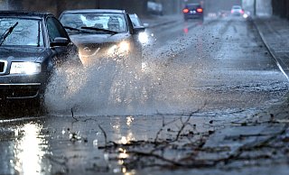 Autos fahren langsam durch eine tiefe Pfütze die sich durch Starkregen gebildet hat. - picture alliance/dpa Autos fahren langsam durch eine tiefe Pfütze die sich durch Starkregen gebildet hat. - picture alliance/dpa
