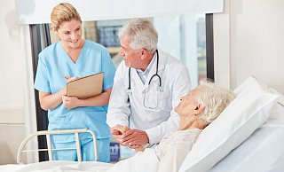 Visite: Arzt und Krankenschwester stehen in einer Klinik am Bett einer Patientin. - picture alliance / Zoonar Visite: Arzt und Krankenschwester stehen in einer Klinik am Bett einer Patientin. - picture alliance / Zoonar