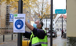Jürgen Klinksiek von der SWK hängt erste Maskenpflicht-Schilder am Rand der Fußgängerzone auf. - Frank-Michael Kiel-Steinkamp Jürgen Klinksiek von der SWK hängt erste Maskenpflicht-Schilder am Rand der Fußgängerzone auf. - Frank-Michael Kiel-Steinkamp