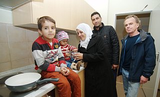 Angekommen: Die syrische Familie Barisho freut sich über die Unterkunft. Sozialarbeiter Rolf Linnemann (r.) und Helfer übergeben gespendete Pakete mit Küchenutensilien an die Flüchtlinge. - thom Angekommen: Die syrische Familie Barisho freut sich über die Unterkunft. Sozialarbeiter Rolf Linnemann (r.) und Helfer übergeben gespendete Pakete mit Küchenutensilien an die Flüchtlinge. - thom
