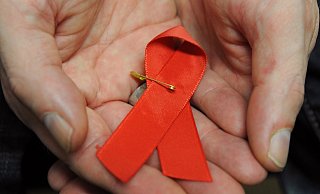 Ein mit dem HI-Virus infizierter Mann mit einer roten Schleife als Symbol der Solidarität mit HIV-Positiven und Aids-Kranken. - Arne Dedert/dpa Ein mit dem HI-Virus infizierter Mann mit einer roten Schleife als Symbol der Solidarität mit HIV-Positiven und Aids-Kranken. - Arne Dedert/dpa