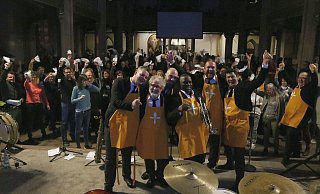In Vesperkirchenschürzen suchen die Sazerac Jazzswingers den Schulterschluss mit dem Publikum. Foto: Burkhard Hoeltzenbein - Burkhard Hoeltzenbein In Vesperkirchenschürzen suchen die Sazerac Jazzswingers den Schulterschluss mit dem Publikum. Foto: Burkhard Hoeltzenbein - Burkhard Hoeltzenbein