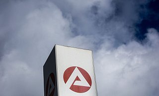 Wolken ziehen über ein Schild der Agentur für Arbeit und dem Berlin-Lichtenberg. - Foto: Carsten Koall/dpa Wolken ziehen über ein Schild der Agentur für Arbeit und dem Berlin-Lichtenberg. - Foto: Carsten Koall/dpa