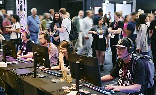 Besucher der Gamescom testen die neuesten Spiele-Highlights an PC-Stationen, während im Hintergrund zahlreiche Messebesucher die Hallen erkunden. - Koelnmesse GmbH/Marvin Ruppert Besucher der Gamescom testen die neuesten Spiele-Highlights an PC-Stationen, während im Hintergrund zahlreiche Messebesucher die Hallen erkunden. - Koelnmesse GmbH/Marvin Ruppert
