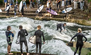 Surfer stehen am Eisbach in München. Zuschauer beobachten gespannt das Geschehen. - IMAGO/Wolfgang Maria Weber Surfer stehen am Eisbach in München. Zuschauer beobachten gespannt das Geschehen. - IMAGO/Wolfgang Maria Weber