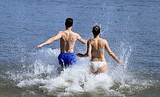 Ein Mann und eine Frau laufen ins kühle Wasser. Nach eher durchwachsenem Wetter ist nun reichlich Sonne angekündigt. - picture alliance/dpa Ein Mann und eine Frau laufen ins kühle Wasser. Nach eher durchwachsenem Wetter ist nun reichlich Sonne angekündigt. - picture alliance/dpa