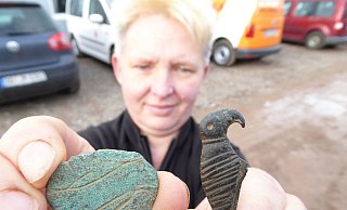 Prunkstücke aus der Siedlung: Andrea Goernemann, Mitarbeiterin des Grabungsteams, zeigt eine Brosche mit stilisierten Tierfiguren und eine Gewandnadel in Vogelform. - Sven Spiong/LWL Prunkstücke aus der Siedlung: Andrea Goernemann, Mitarbeiterin des Grabungsteams, zeigt eine Brosche mit stilisierten Tierfiguren und eine Gewandnadel in Vogelform. - Sven Spiong/LWL