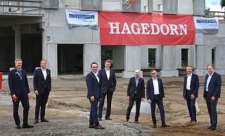 Bürgermeister Henning Schulz (v.l.), Rick Mädel (Hagedorn Revital), Thomas Hagedorn, Gert-Manfred Hornig (Post), Heiko Riedel (DPDHL Real Estate), Bernd Jungholt (Bremer), Andreas Goltz (DPDHL) und Torsten Schuff (Vorstand Bremer AG) freuen sich bei aller Distanzwahrung über den raschen Baufortschritt. - Andreas Frücht Bürgermeister Henning Schulz (v.l.), Rick Mädel (Hagedorn Revital), Thomas Hagedorn, Gert-Manfred Hornig (Post), Heiko Riedel (DPDHL Real Estate), Bernd Jungholt (Bremer), Andreas Goltz (DPDHL) und Torsten Schuff (Vorstand Bremer AG) freuen sich bei aller Distanzwahrung über den raschen Baufortschritt. - Andreas Frücht