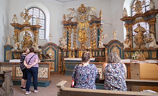 Einige Besucherinnen der Paderborner Liborikapelle halten vor dem geschnitzten Hochaltar inne. - Niklas Tüns Einige Besucherinnen der Paderborner Liborikapelle halten vor dem geschnitzten Hochaltar inne. - Niklas Tüns