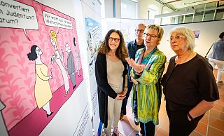 Ausstellungskuratorin Myriam Halberstam (v. l.) diskutiert mit Gerd Kurbjuhn von der VHS, der Antisemitismusbeauftragten Sylvia Löhrmann und Beate Ehlers einen Cartoon zu Verschwörungstheorien. - Sarah Jonek Ausstellungskuratorin Myriam Halberstam (v. l.) diskutiert mit Gerd Kurbjuhn von der VHS, der Antisemitismusbeauftragten Sylvia Löhrmann und Beate Ehlers einen Cartoon zu Verschwörungstheorien. - Sarah Jonek