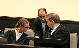 Zum Auftakt des Verfahrens besprechen sich die Verteidiger Lena Holtkötter und Maximilian Steinert (r.) mit einem der Übersetzer. - Rajkumar Mukherjee Zum Auftakt des Verfahrens besprechen sich die Verteidiger Lena Holtkötter und Maximilian Steinert (r.) mit einem der Übersetzer. - Rajkumar Mukherjee
