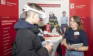 Per VR-Brille als Kfz-Mechatroniker unters Auto: Marie-Kristin Janzen lässt Schüler am Stand der Stadt in die Berufswelt eintauchen. - Dieckmann-Fotodesign l Bielefeld Per VR-Brille als Kfz-Mechatroniker unters Auto: Marie-Kristin Janzen lässt Schüler am Stand der Stadt in die Berufswelt eintauchen. - Dieckmann-Fotodesign l Bielefeld