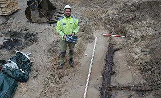 Ein Grabungsarbeiter zeigt im März die Ausmaße eines der entdeckten Baumstämme. - EggensteinExca Ein Grabungsarbeiter zeigt im März die Ausmaße eines der entdeckten Baumstämme. - EggensteinExca