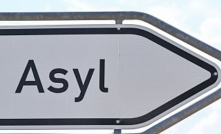 Das Wort «Asyl» steht auf einem Wegweiser zur Erstaufnahme-Einrichtungen (EAE) des Landes Brandenburg in Eisenhüttenstadt. - Patrick Pleul/dpa Das Wort «Asyl» steht auf einem Wegweiser zur Erstaufnahme-Einrichtungen (EAE) des Landes Brandenburg in Eisenhüttenstadt. - Patrick Pleul/dpa