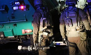 Polizisten des SEK stehen mit ihren Werkzeugen hinter einem gepanzerten Polizeifahrzeug in der Einfahrt zu einem Haus in Dortmund. In ganz NRW wurden mehrere Wohnungen durchsucht, sechs Rocker der Bandidos wurden verhaftet. - picture alliance/dpa Polizisten des SEK stehen mit ihren Werkzeugen hinter einem gepanzerten Polizeifahrzeug in der Einfahrt zu einem Haus in Dortmund. In ganz NRW wurden mehrere Wohnungen durchsucht, sechs Rocker der Bandidos wurden verhaftet. - picture alliance/dpa