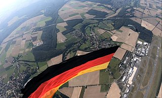 Aus der Luftperspektive ist links neben der Riesen-Flagge Wewelsburg zu sehen, oberhalb liegen Ahden und die A 44, rechts der Airport. - Cypres-Demo-Team Aus der Luftperspektive ist links neben der Riesen-Flagge Wewelsburg zu sehen, oberhalb liegen Ahden und die A 44, rechts der Airport. - Cypres-Demo-Team