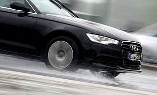 Ein Auto fährt durch eine riesige Pfütze. Fährt es zu schnell oder sind die Reifen nicht im besten Zustand, kommt es dann schnell zu Aquaplaning. - Verwendung weltweit Ein Auto fährt durch eine riesige Pfütze. Fährt es zu schnell oder sind die Reifen nicht im besten Zustand, kommt es dann schnell zu Aquaplaning. - Verwendung weltweit