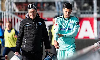 Raphael Obermair hält sich den lädierten rechten Arm und wird von Mannschaftsarzt Hans-Walter Hemmen in die Kabine des Holstein-Stadions begleitet. - Imago Images Raphael Obermair hält sich den lädierten rechten Arm und wird von Mannschaftsarzt Hans-Walter Hemmen in die Kabine des Holstein-Stadions begleitet. - Imago Images