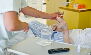 Eine Krankenpflegerin reicht einem Patienten ein Glas Wasser. - Daniel Karmann/dpa Eine Krankenpflegerin reicht einem Patienten ein Glas Wasser. - Daniel Karmann/dpa