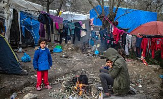 Eine Migrantenfamilie versucht, sich an einem kleinen Feuer in einem provisorischen Lager neben dem Lager in Moria aus Lesbos zu wärmen. - picture alliance/dpa Eine Migrantenfamilie versucht, sich an einem kleinen Feuer in einem provisorischen Lager neben dem Lager in Moria aus Lesbos zu wärmen. - picture alliance/dpa