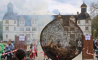 Bei der Aktion von Künstler Arndt Drossel wird eine symbolische Weltkugel aus Draht entflammt, um sie gemeinsam wieder zu löschen. - Moritz Jülich Bei der Aktion von Künstler Arndt Drossel wird eine symbolische Weltkugel aus Draht entflammt, um sie gemeinsam wieder zu löschen. - Moritz Jülich