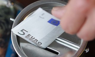 Ein Fünf-Euro-Schein wird in eine Spendendose gesteckt. Die Weihnachtszeit ist eine Zeit des Gebens. - picture alliance / Bernd Thissen/dpa Ein Fünf-Euro-Schein wird in eine Spendendose gesteckt. Die Weihnachtszeit ist eine Zeit des Gebens. - picture alliance / Bernd Thissen/dpa