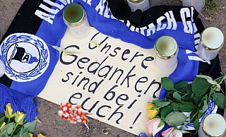 Kerzen, ein Fanschal von Arminia Bielefeld und ein Zettel mit der Aufschrift "Unsere Gedanken sind bei Euch!" sind am Tatort vor dem Club "Cutie" in der Innenstadt zu sehen. - Friso Gentsch/dpa Kerzen, ein Fanschal von Arminia Bielefeld und ein Zettel mit der Aufschrift "Unsere Gedanken sind bei Euch!" sind am Tatort vor dem Club "Cutie" in der Innenstadt zu sehen. - Friso Gentsch/dpa