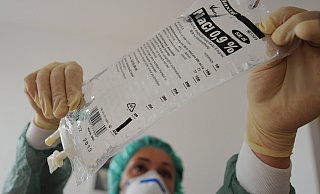 Eine Krankenschwester hängt eine Flasche mit Kochsalzlösung in einen Infusionsständer. Die für viele Behandlungen wichtige Flüssigkeit ist derzeit nicht ausreichend vorhanden. - picture alliance / dpa Eine Krankenschwester hängt eine Flasche mit Kochsalzlösung in einen Infusionsständer. Die für viele Behandlungen wichtige Flüssigkeit ist derzeit nicht ausreichend vorhanden. - picture alliance / dpa