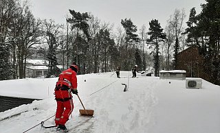Mit Schneeschiebern und Besen machte man der kalt-weißen Pracht auf dem langen Flachdach des Gebäudes den Garaus und beförderte sie herunter. - Feuerwehr Espelkamp Mit Schneeschiebern und Besen machte man der kalt-weißen Pracht auf dem langen Flachdach des Gebäudes den Garaus und beförderte sie herunter. - Feuerwehr Espelkamp