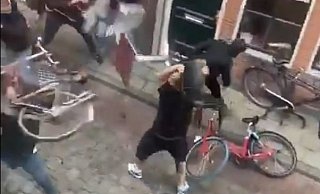 Das Video zeigt unter anderem, wie ein Mann (r.) einen Stuhl in die Gruppe der Bielefelder Fans schleudern will. Diese wehren sich, indem sie Fahrräder und Tische in seine Richtung schleudern. - Screenshot: Twitter / sandervh1998 Das Video zeigt unter anderem, wie ein Mann (r.) einen Stuhl in die Gruppe der Bielefelder Fans schleudern will. Diese wehren sich, indem sie Fahrräder und Tische in seine Richtung schleudern. - Screenshot: Twitter / sandervh1998