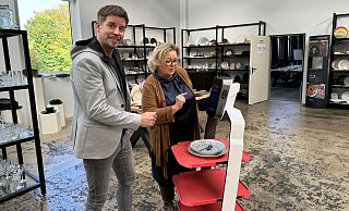 Steven Murphy vom Bielefelder Gastronomie-Ausstatter Schulze und Hase erklärt der ostwestfälischen Dehoga-Geschäftsführerin Regine Tönsing, wie ein Service-Roboter programmiert und eingesetzt wird. - mika Steven Murphy vom Bielefelder Gastronomie-Ausstatter Schulze und Hase erklärt der ostwestfälischen Dehoga-Geschäftsführerin Regine Tönsing, wie ein Service-Roboter programmiert und eingesetzt wird. - mika