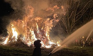 Als es auf der Lohe stockdunkel ist, entzünden die Besucher ein mächtiges Osterfeuer. Damit die Flammen nicht auf die umliegenden Bäume übergreifen, halten Brandbekämpfer Wasserpistolen auf die Äste. - Elke Niedringhaus-Haasper Als es auf der Lohe stockdunkel ist, entzünden die Besucher ein mächtiges Osterfeuer. Damit die Flammen nicht auf die umliegenden Bäume übergreifen, halten Brandbekämpfer Wasserpistolen auf die Äste. - Elke Niedringhaus-Haasper