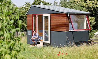 "Tiny-House" nennt man ein solch kleines Gebäude, vor dem Sascha Wagner sitzt. Die Grünen in Verl wollen wissen, ob es für diese minimalistische Wohnform auch in Verl Grundstücke geben könnte. - Symbolfoto/ picture alliance "Tiny-House" nennt man ein solch kleines Gebäude, vor dem Sascha Wagner sitzt. Die Grünen in Verl wollen wissen, ob es für diese minimalistische Wohnform auch in Verl Grundstücke geben könnte. - Symbolfoto/ picture alliance