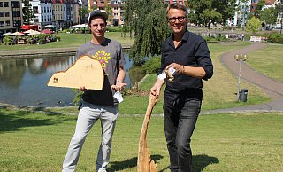 Designer Jan Petzold (l.) übergibt Markus Runte vom Stadtmuseum ausgewähltes und signiertes „Heimat Holz“, gesammelte Baumreste aus dem Paderquellgebiet. - Stadt Paderborn/Stadtmuseum Designer Jan Petzold (l.) übergibt Markus Runte vom Stadtmuseum ausgewähltes und signiertes „Heimat Holz“, gesammelte Baumreste aus dem Paderquellgebiet. - Stadt Paderborn/Stadtmuseum