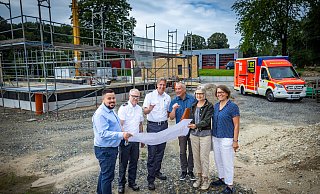 Tobias Mowitz (v.l., Firma Höfer), Stefan Laker, Dirk Fortmeier (Feuerwehr), Matthias Krieter (Höfer), Bettina Stöckel-Schepp und Ulrike Mößinger (ISB) schauen sich die Pläne für die neue Rettungswache (im Hintergrund) an. - Sarah Jonek Fotografie Tobias Mowitz (v.l., Firma Höfer), Stefan Laker, Dirk Fortmeier (Feuerwehr), Matthias Krieter (Höfer), Bettina Stöckel-Schepp und Ulrike Mößinger (ISB) schauen sich die Pläne für die neue Rettungswache (im Hintergrund) an. - Sarah Jonek Fotografie