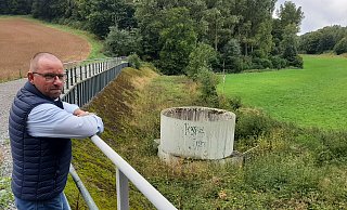 Ortsvorsteher Hubertus Kuhaupt weist auf Einlauf, Damm und Spundwand des Rückhaltebeckens hin. Die Dimensionen des Bauwerks sind strittig. - Dieter Scholz Ortsvorsteher Hubertus Kuhaupt weist auf Einlauf, Damm und Spundwand des Rückhaltebeckens hin. Die Dimensionen des Bauwerks sind strittig. - Dieter Scholz