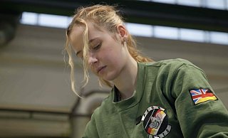 Jasmin ist leidenschaftliche Schrauberin für die britische Armee. An ihrem Ärmel die deutsche Fahne und der Union Jack. - Screenshot Jasmin ist leidenschaftliche Schrauberin für die britische Armee. An ihrem Ärmel die deutsche Fahne und der Union Jack. - Screenshot
