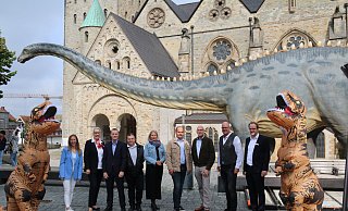 Die Organisatoren von "Dinoborn" posieren vor dem Paderborner Dom mit dem an einem Baum naschenden Diplodocus. - Maria Kalemi Die Organisatoren von "Dinoborn" posieren vor dem Paderborner Dom mit dem an einem Baum naschenden Diplodocus. - Maria Kalemi